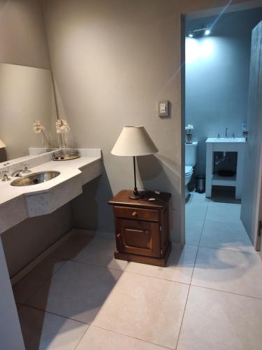 a bathroom with a sink and a lamp on a table at Apart La Empedrada in Trapiche