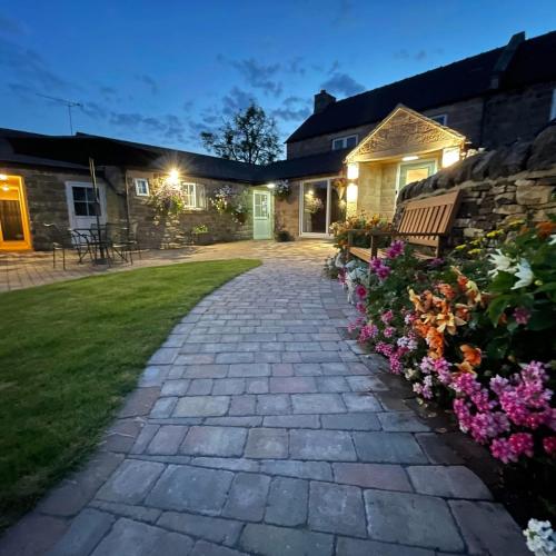 a stone walkway in front of a house with flowers at Crich Lane Farm in Alfreton