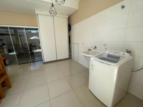 a white bathroom with a sink and a washing machine at Sobrado Premium - Zona Sul in Maringá