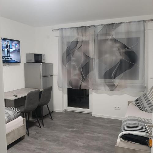 a living room with a table and a desk with a window at Five Rooms in Sinsheim