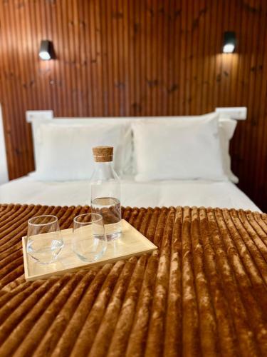 a bottle and two glasses on a tray on a bed at Cantinho D` Alice in Armamar