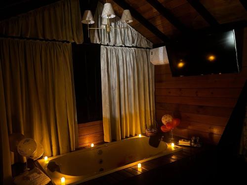 a bathroom with a tub with candles and a window at Romantic nature retreat | Hot tub and fireplace in São Pedro de Alcântara
