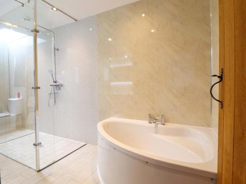 a bathroom with a tub and a glass shower at Bwthyn Y Bugail Shepherd's Cottage in Oswestry