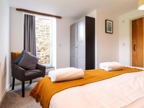 a bedroom with a bed and a chair and a window at Bwthyn Y Bugail Shepherd's Cottage in Oswestry