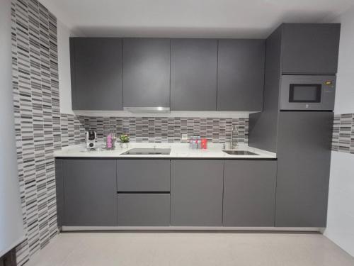 a kitchen with gray cabinets and a sink at Mercurio Blanco-Zona Catedral in León