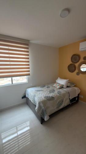 a bedroom with a bed and a window with blinds at Cartagena Serena Del Mar INAWA in Cartagena de Indias
