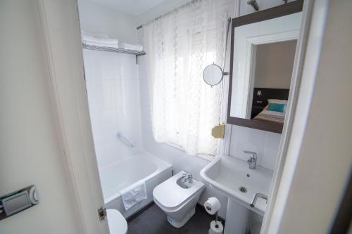 a white bathroom with a sink and a toilet at Hostal Cabo Mayor in Santander