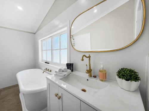 a white bathroom with a sink and a mirror at Aveline Cottage in Cessnock