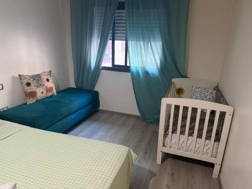 a bedroom with a crib and a blue couch at Appartement de lux avec piscine in Mohammedia