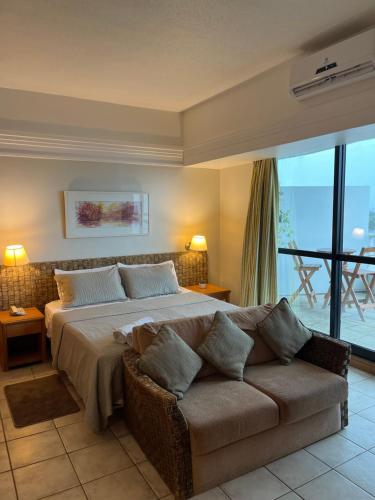 a bedroom with a large bed and a couch at Flat Tropical Hotel Com Varanda Vista Espetacular in Manaus