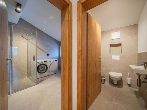 a bathroom with a toilet and a sink and a washing machine at Glückauf in Krimml