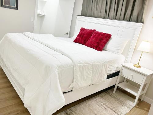 a white bed with a red pillow on it at DeHaven in Edmonton