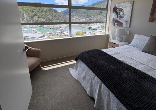 a bedroom with a large window with a view of a harbor at Waterfront Retreat on the foreshore of Queen Charlotte Sound in Picton