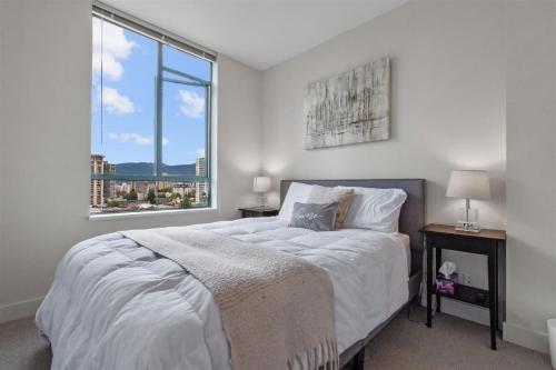 a white bedroom with a large bed and a window at Sub-Penthouse view condo in Downtown in Vancouver