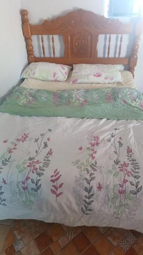 a bed with a white comforter with flowers on it at mendes in Água Boa