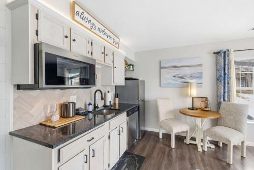 a kitchen with white cabinets and a table and a refrigerator at TaneyCoMo Topia Quaint Studio in Branson