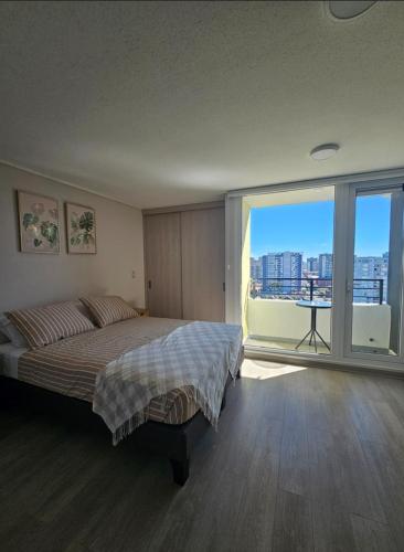 a bedroom with a bed and a large window at Modern fully equipped studio with parking in Concepción
