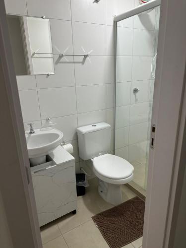 a white bathroom with a toilet and a sink at Vila Estrela in Ponta Grossa