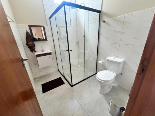 a bathroom with a toilet and a glass shower at Casa, Delfinópolis - Serra da Canastra, MG in Delfinópolis