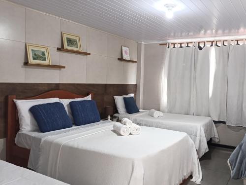 a hotel room with two beds and a window at Hospedagem Doce Lar - Casa Manacá in Teresópolis
