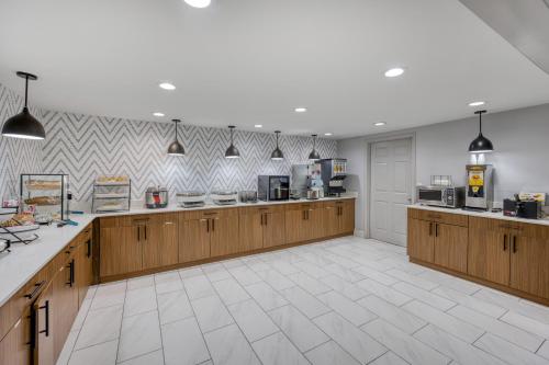 a large kitchen with wooden cabinets and a white tile floor at Best Western Greensboro Coliseum Inn in Greensboro