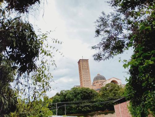 a tall building in the distance with trees in the foreground at pousada benção in Aparecida
