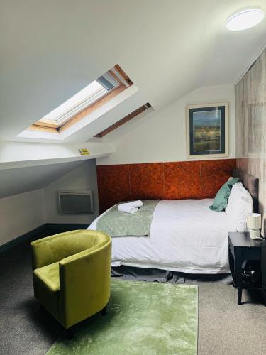a bedroom with a bed and a green chair at Park City Rooms in Manchester
