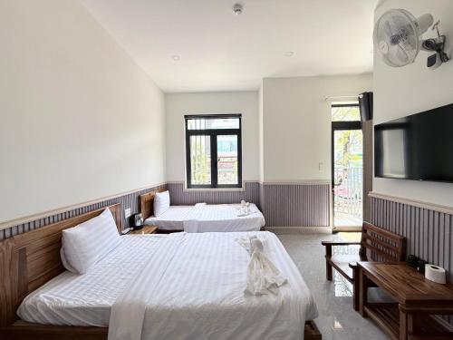 a bedroom with two beds and a flat screen tv at Motel Nam Nguyên in Buôn Kô Sir