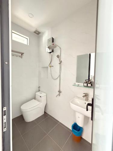 a white bathroom with a toilet and a sink at Motel Nam Nguyên in Buôn Kô Sir