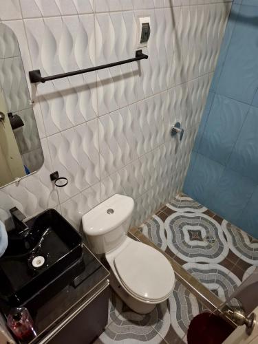 a bathroom with a white toilet and a sink at Lily's Apartamentos in Cochabamba