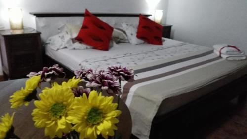 a bed with yellow and red pillows and flowers on it at Giron Chill Out Hotel Boutique in Girón