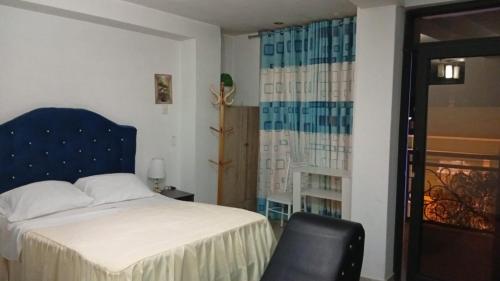 a bedroom with a bed and a chair and a window at Hotel Diamante Azul in Huancayo
