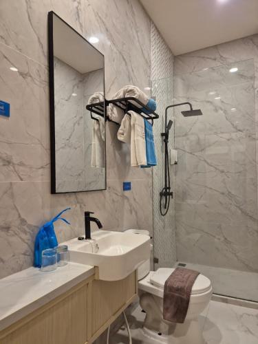 a bathroom with a sink and a toilet and a mirror at True Blue Hotel Menteng in Jakarta