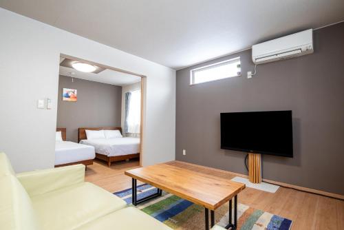 a living room with a tv and a couch and a table at Stay In Biei in Biei
