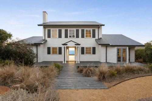 a white house with a wooden walkway in front of it at The Veranda - Panoramic Bay Views Private Beach Access Pool in Mount Eliza