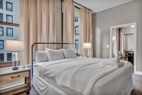a bedroom with a large white bed and two windows at Central Downtown Loft | Parking•Gym•Security in Cleveland