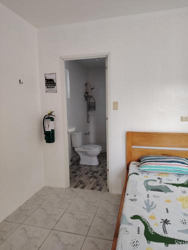 a bedroom with a bed and a bathroom with a toilet at Kathleens Vacation Place in Moalboal