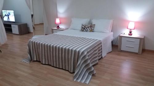 a bedroom with a bed with a striped blanket and two lamps at Casa Claudia - Pool and Wifi in Silves