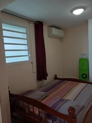 a small bedroom with a bed and a window at Santa Marta in Rivière-Pilote