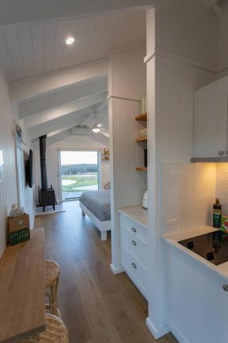 a room with a kitchen and a living room with a bed at Banjos Cabin Gippsland - Luxury Eco Stay w King Bed & Pond Valley Views in Seaton