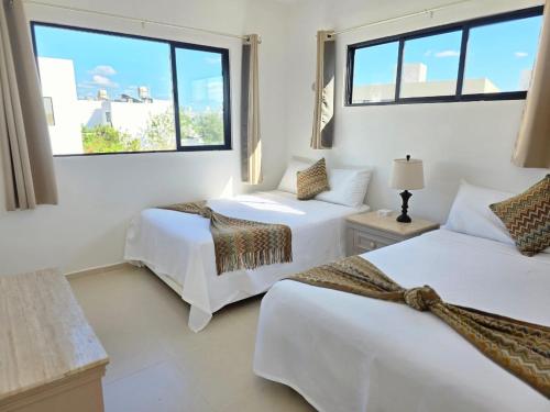 two beds in a room with two windows at Casa Havana Mid in Mérida