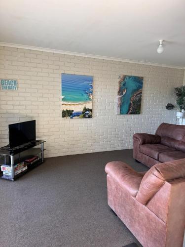 a living room with a couch and a flat screen tv at Steps to Sand, Surf & the Bowlo in Tathra