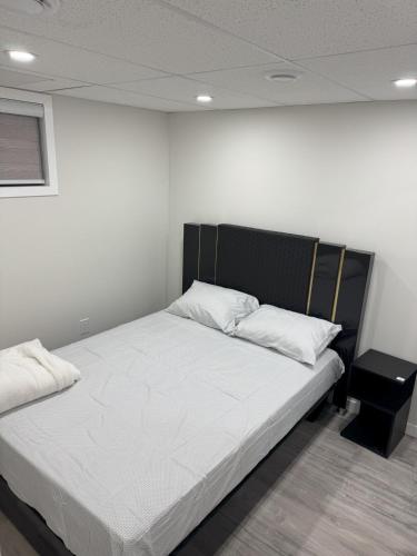 a bedroom with a bed with white sheets and pillows at Urban Haven Suite in Winnipeg