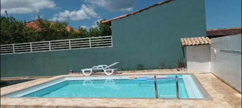 a pool with two chairs and a house at Casa c ar cond, wifi, a 5 min Orla da Lagoa Para Famílias in Araruama