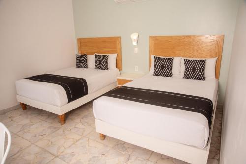 two beds in a small room with two beds at Hotel La Siesta, Gomez Palacio in Gómez Palacio