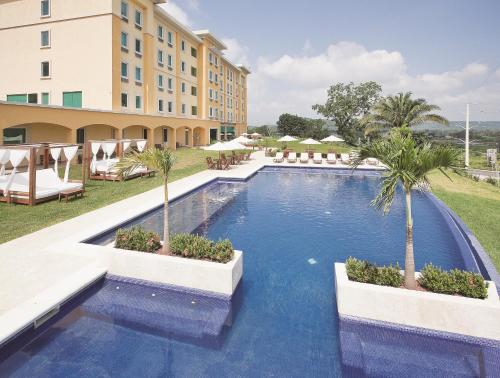 a pool at a resort with palm trees and chairs at La Quinta by Wyndham Poza Rica in Poza Rica de Hidalgo