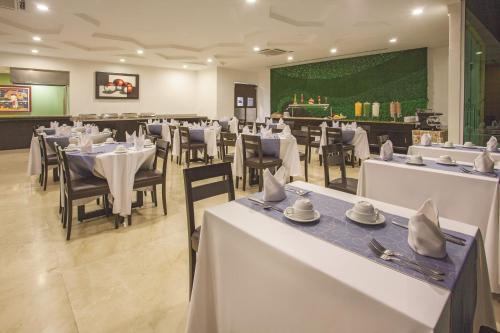 a restaurant with white tables and chairs and a green wall at La Quinta by Wyndham Poza Rica in Poza Rica de Hidalgo