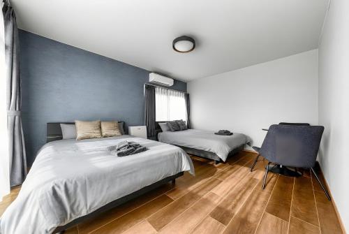 a bedroom with two beds and a chair at The Villa Seaside in Abashiri