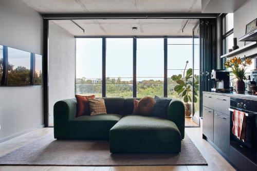 a living room with a green couch and large windows at Eastlake Retreat Kingston in Kingston 