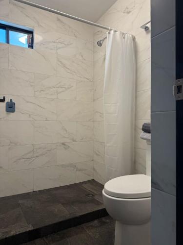 a white bathroom with a toilet and a shower at Punta Lobos in Reynosa